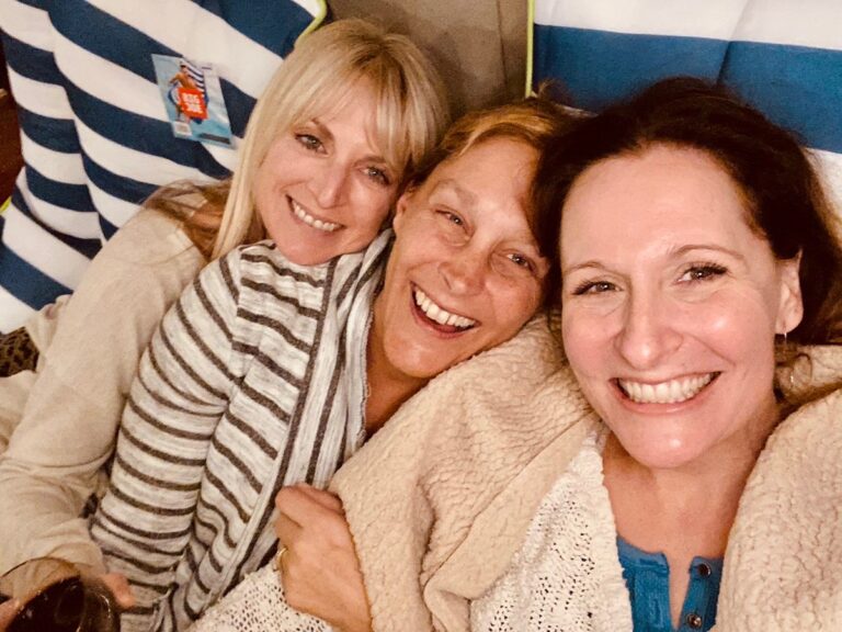 Liz Childers smiling & hugging 2 of her crew